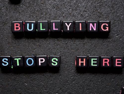 bullying stops here written in plastic beads on a black slab surface
